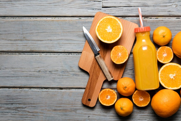 Frischer Orangensaft in einer Flasche mit Orangen auf rustikalem Holzhintergrund