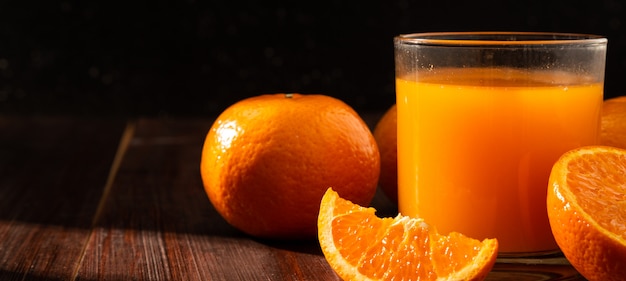Frischer Orangensaft in Glas und Orangenfrucht auf Holztisch