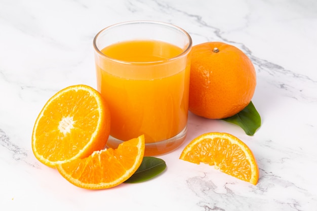 Frischer Orangensaft in Glas- und Orangenfrucht auf weißem Marmortischhintergrund