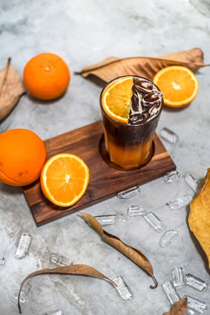 Frischer orangensaft und zitrusfrüchte vitamin c hat gesundheitliche vorteile, frisch, schuppig, süß, auf einem holztablett, blättern und runden eiswürfeln angeordnet.