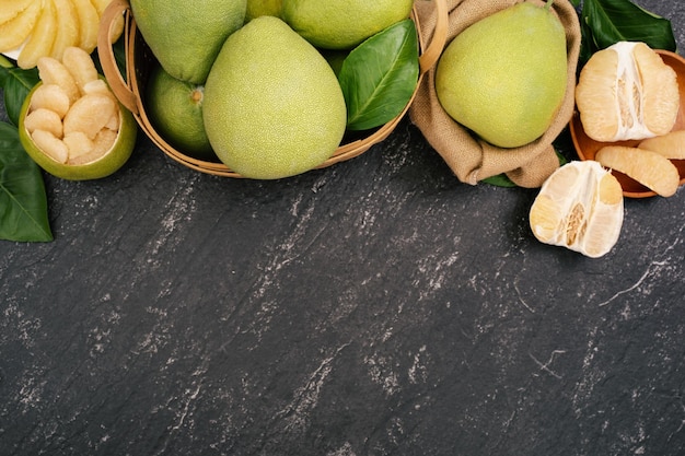 Frischer Pomelo Pummelo Grapefruit Shaddock im Bambuskorb mit Blatt auf dunkelschwarzem Schieferhintergrund Konzept der saisonalen Früchte Draufsicht Flache Lage