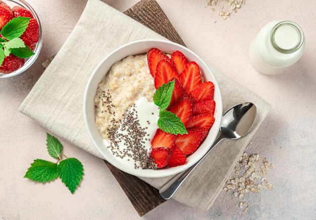 Frischer Porridge mit Beeren und Chiasamen auf hellrosa Hintergrund