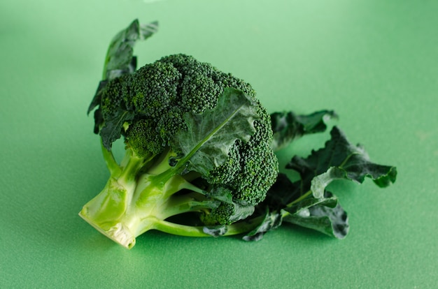 Frischer roher Brokkoli auf grünem Hintergrund. Bio-Lebensmittel-Konzept