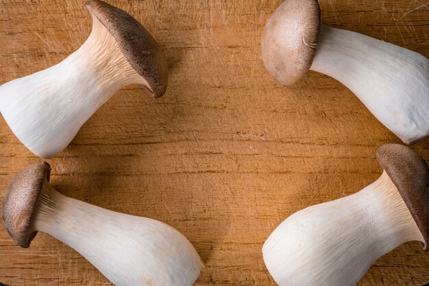 Foto frischer roher könig, königliche austernpilze auf dunklem holztisch, vorbereitung