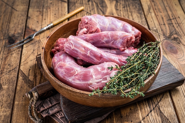 Frischer roher Truthahnhalsfleisch in einem Holzteller mit Thymian. Holztisch. Draufsicht.