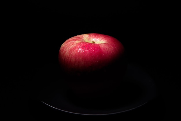 Frischer roter Apfel Auf einem schwarzen Hintergrund mit Wassertröpfchen fallen Lichter mit Platz für Text