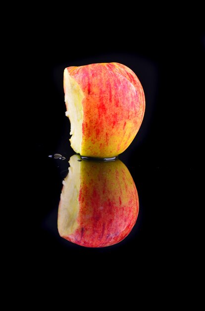 Frischer roter Apfel mit Wassertropfen auf schwarzem Hintergrund