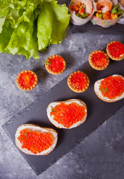 Frischer roter Kaviar auf Brot. Sandwiches mit rotem Kaviar und Törtchen mit rotem Kaviar. Delikatessen. Gourmet Essen