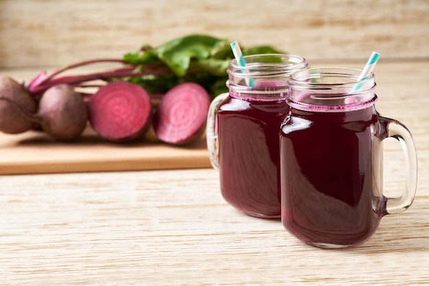 Frischer Rübensaft in einem Einmachglas. Szene mit Zutaten gegen einen Holztisch.