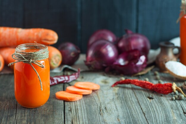 Frischer Saft der Karotte in einem Glasbehälter unter dem Gemüse