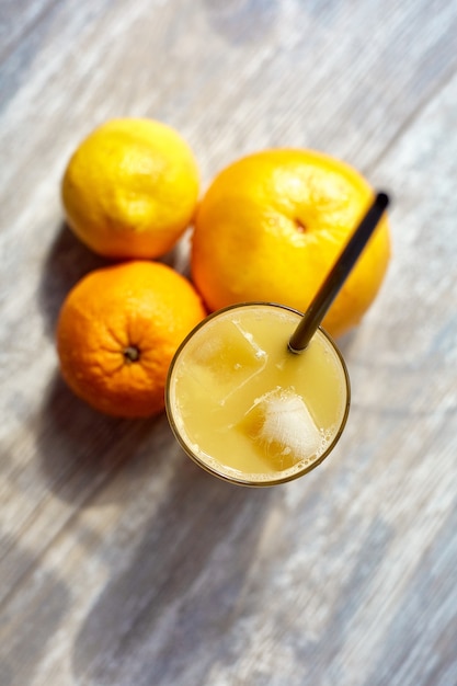 Foto frischer saft in einem glas mit eis auf dem tisch und orangen