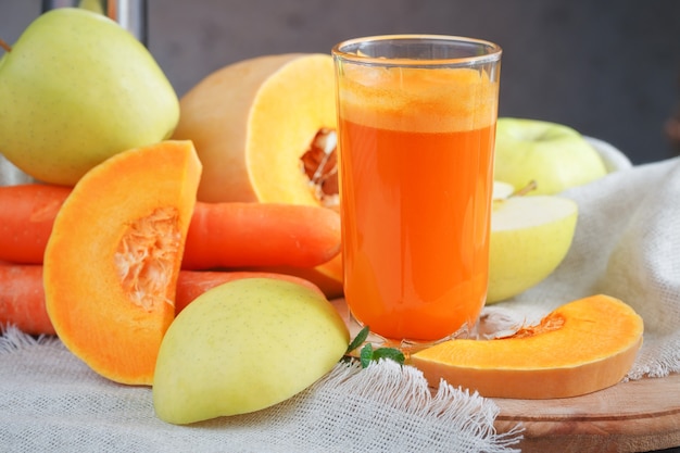 Frischer Saft, Obst und Gemüse auf einem Holztisch mischen