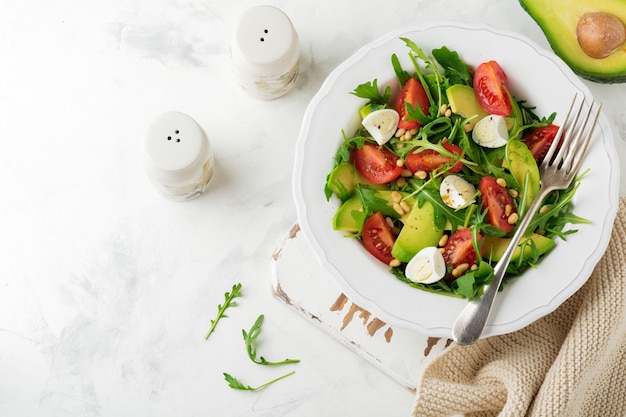 Frischer Salat aus Rucola, Tomate, Avocado, Olivenöl, Nüssen und Wachteleiern