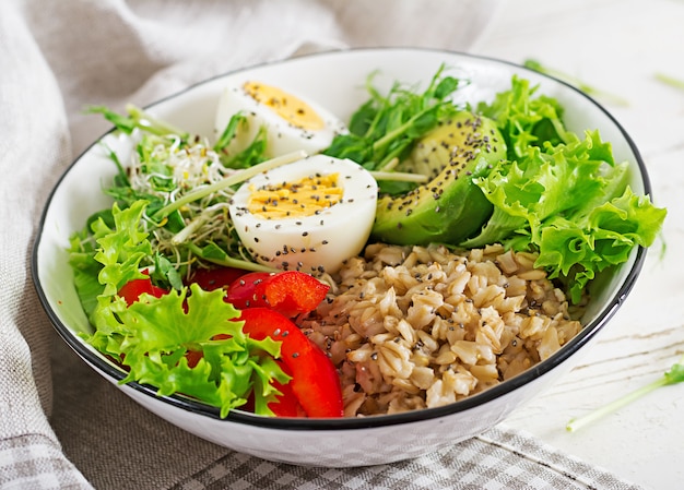 Frischer Salat. Frühstücksschüssel mit Haferflocken, Paprika, Avocado, Salat, Microgreens und gekochtem Ei. Gesundes Essen. Vegetarische Buddha-Schale.