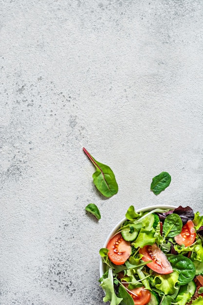 Frischer Salat mit frischem Gemüse, reifen Tomaten, Gurkensalat und Mikrogrün in einer Schüssel auf grauem Hintergrund Gesundes Rohkostkonzept Platz für Textkopierraum