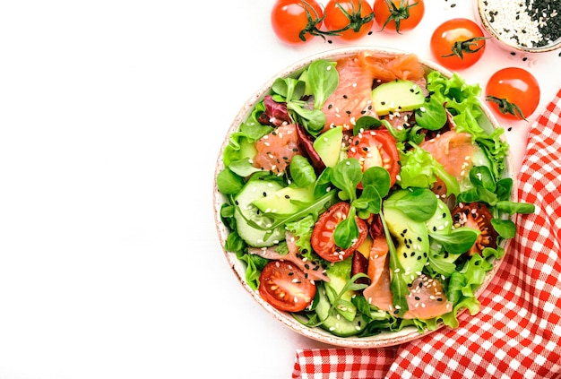 Frischer Salat mit gesalzenem Lachs, Avocado, Gurken, Sesamsamen, Olivenöl, Tomaten und gemischten Kräutern. Weißer Hintergrund, Draufsicht, Kopienraum