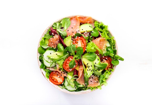 Foto frischer salat mit gesalzenem lachs, avocado, gurken, sesamsamen, olivenöl, tomaten und gemischten kräutern. weißer hintergrund, draufsicht, kopienraum