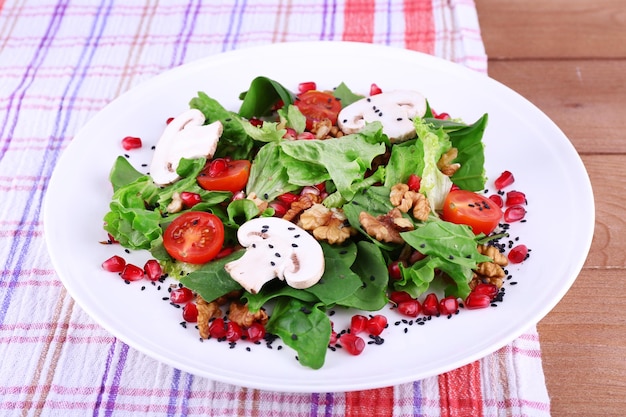 Frischer Salat mit grünem Granat und Gewürzen auf dem Teller auf dem Tisch in der Nähe