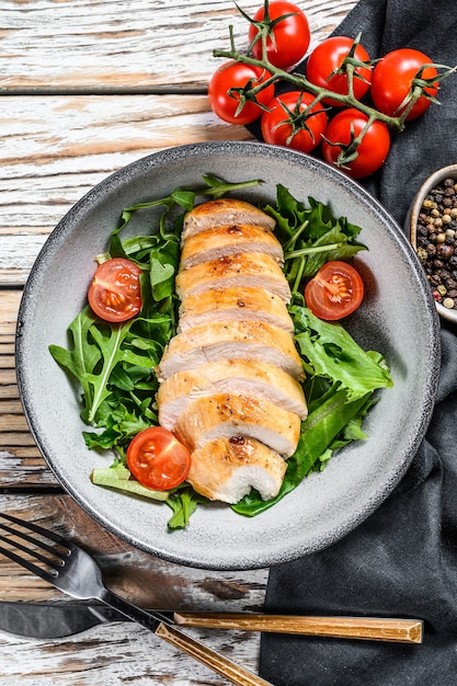 Frischer Salat mit Hühnerbrust, Rucola und Tomate. Weißer Hintergrund. Draufsicht. Speicherplatz kopieren