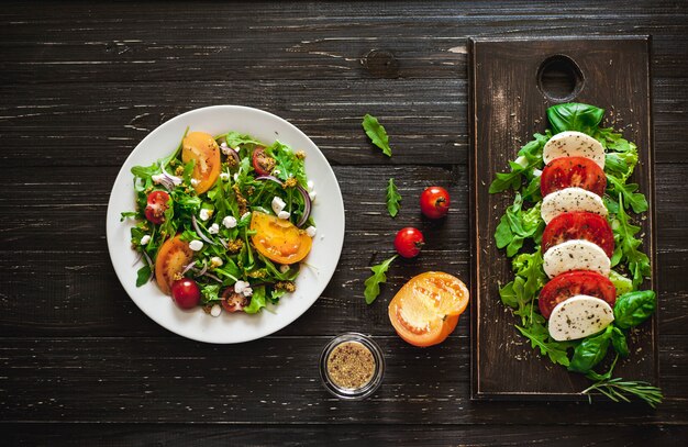 Frischer Salat mit Tomaten, gemischtem Grün, Nüssen, Eiern, auf hölzernem Hintergrund. Gesundes Essen.