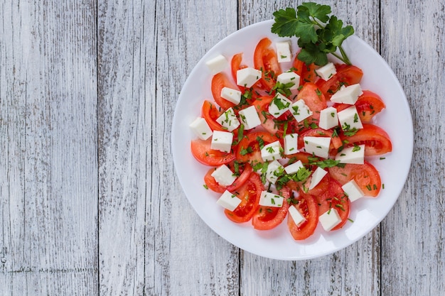 Frischer Salat mit Tomaten, Mozzarella und Kräutern auf weißem Holztisch