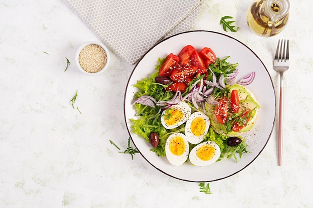 Frischer Salat mit Tomaten, Oliven, gekochten Eiern und Sandwich mit Ricotta-Käse-Avocado. Draufsicht flach liegend