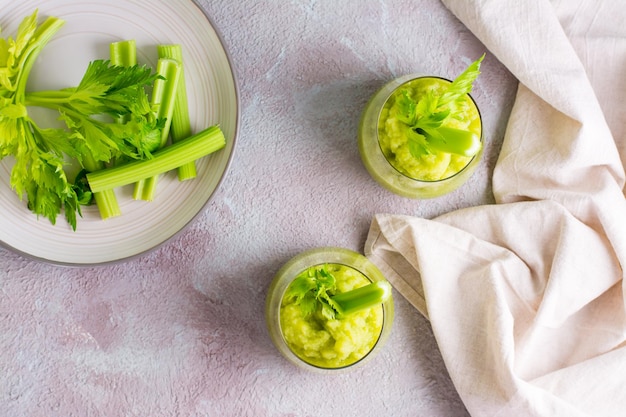 Frischer Sellerie-Smoothie in Gläsern und Kochzutaten auf dem Tisch. Vegetarische Ernährung Detox-Lebensmittel. Ansicht von oben