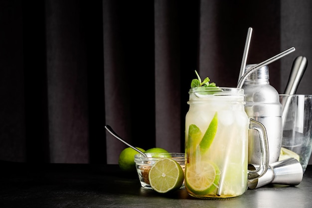 Frischer Sommer-Caipirinha-Cocktail auf schwarzem Hintergrund mit grüner Fruchtlimette auf dem Tisch