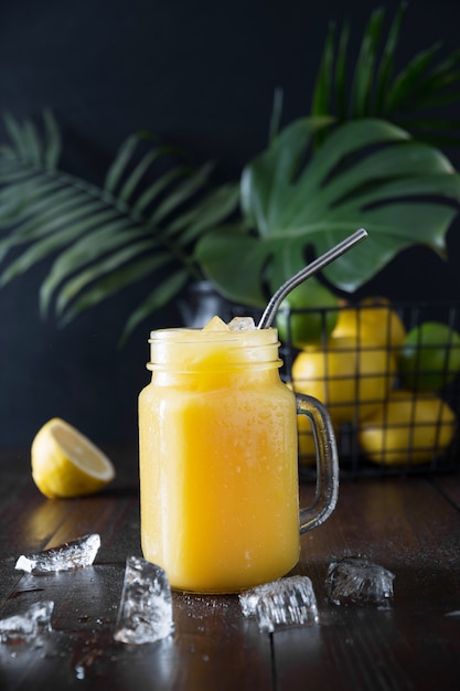 Frischer Sommerfruchtsaft mit Zitrone auf dunklem tropischem Hintergrund. Nahansicht.