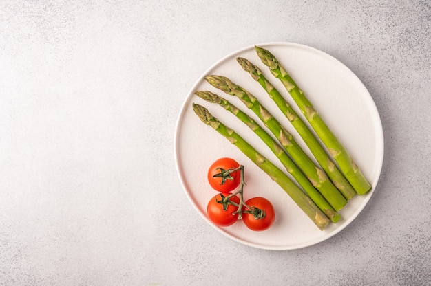 Frischer Spargel und Kirschtomaten auf einem weißen Teller