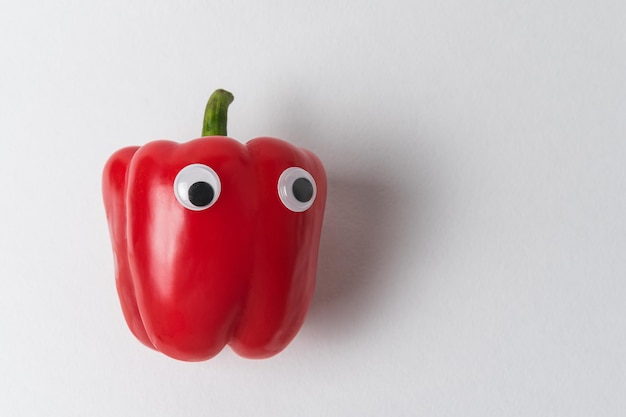 Frischer süßer Glockenpaprika mit lustigem Gesicht. Roher roter Paprika mit Kulleraugen.