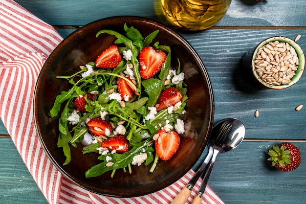 Frischer vegetarischer Diät-Salat mit Erdbeeren, Aragula und Käse. Hintergrund des Lebensmittelrezepts. Nahansicht. Draufsicht.