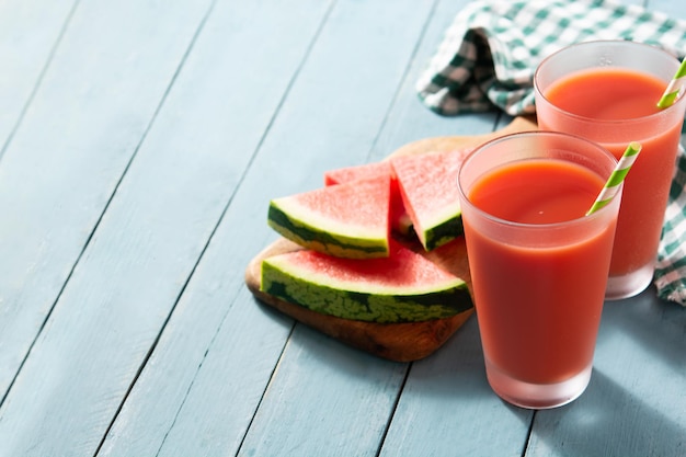 Frischer Wassermelonensaft mit Eis auf blauem Holztisch Platz kopieren