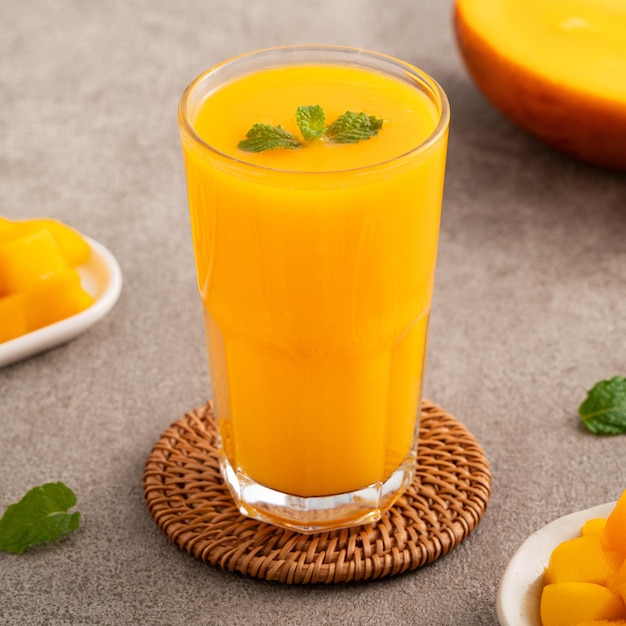 Foto frischer, wunderschöner, köstlicher mangosaft nahaufnahme des designkonzepts eines smoothie-kaltgetränks in einer glasschale mit glasstroh auf grauem tischhintergrund