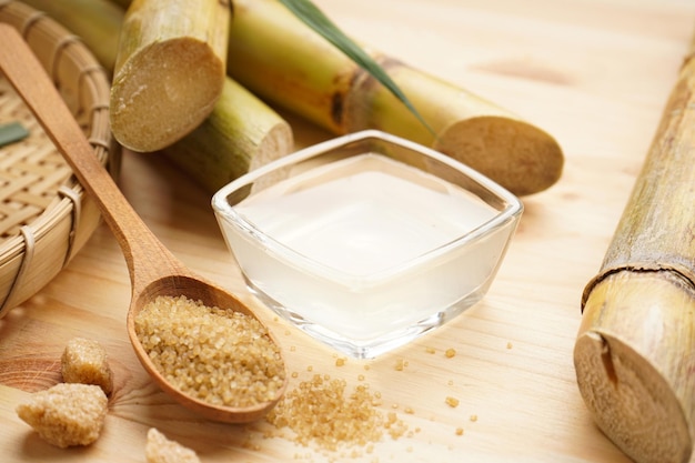 Frischer Zuckerrohrsaft und brauner Zucker auf einem hölzernen Hintergrund Nahaufnahme