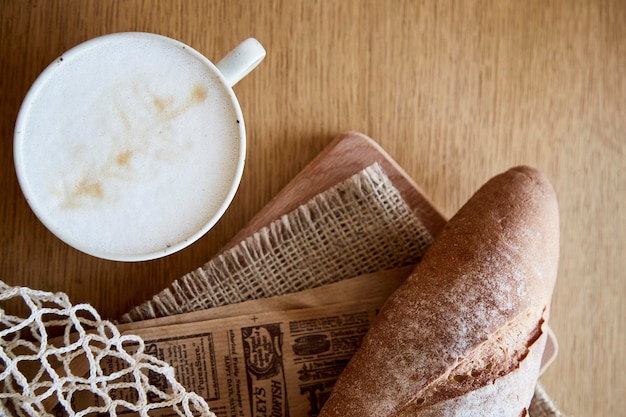 Frisches Baguette mit Cappuccino auf Holztisch Französisches Frühstück