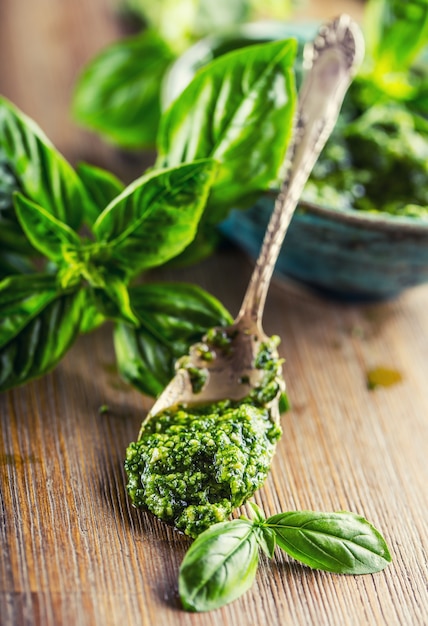 Frisches Basilikum verlässt Pesto auf Holztisch.