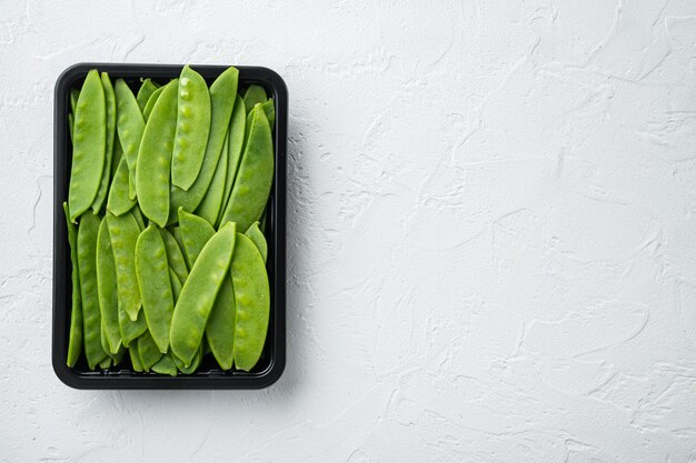 Frisches Bio-Mangetout, auch als Zuckerschoten-Set bekannt, in Plastikbehältern auf weißem Stein