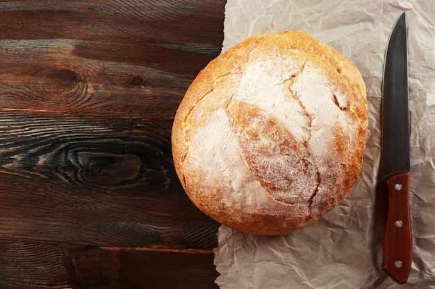 Foto frisches brot auf papier auf hölzern hintergrund