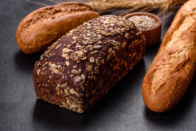 Frisches Brot auf schwarzem Hintergrund, Draufsicht, Kopienraum. Hausgemachte, frisch gebackene verschiedene Weizen- und Roggenbrote