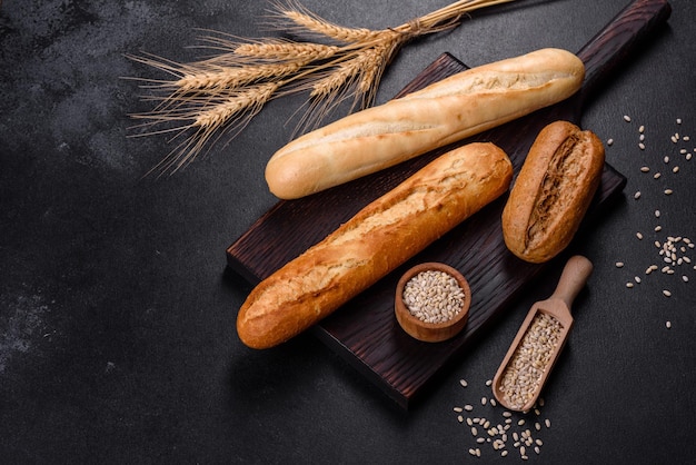 Frisches Brot auf schwarzem Hintergrund, Draufsicht, Kopienraum. Hausgemachte, frisch gebackene verschiedene Weizen- und Roggenbrote