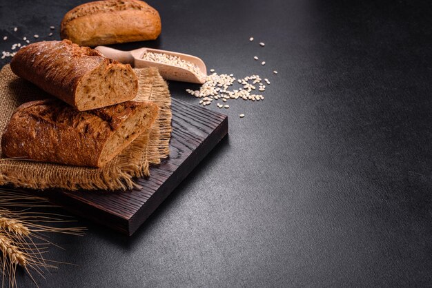 Frisches Brot auf schwarzem Hintergrund, Draufsicht, Kopienraum. Hausgemachte, frisch gebackene verschiedene Weizen- und Roggenbrote