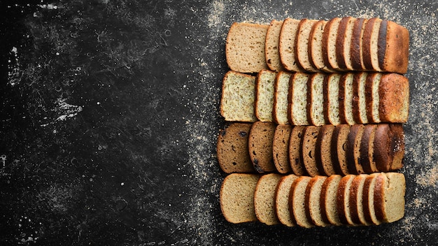 Frisches Brot Auswahl an geschnittenem Schwarz-Weiß-Brot Draufsicht Schwarzer Stein Hintergrund rustikalen Stil