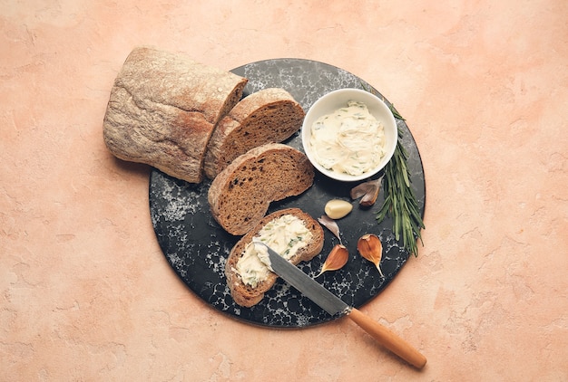 Foto frisches brot, knoblauchbutter und zutaten auf farbigem hintergrund