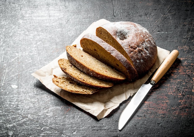 Frisches Brot mit einem Messer in Scheiben schneiden