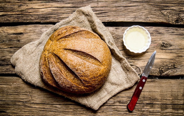 Frisches Brot mit Messer und Öl. Auf dem Holztisch. Draufsicht