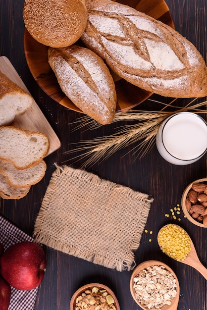 Frisches Brot mit Milch auf schwarzem Holztisch.