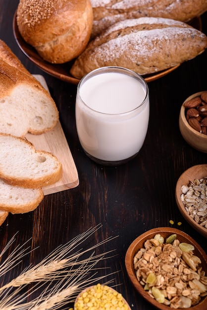 Frisches Brot mit Milch auf schwarzem Holztisch.