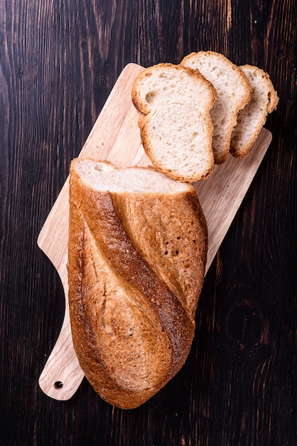 Frisches Brot mit Milch auf schwarzem Holztisch.