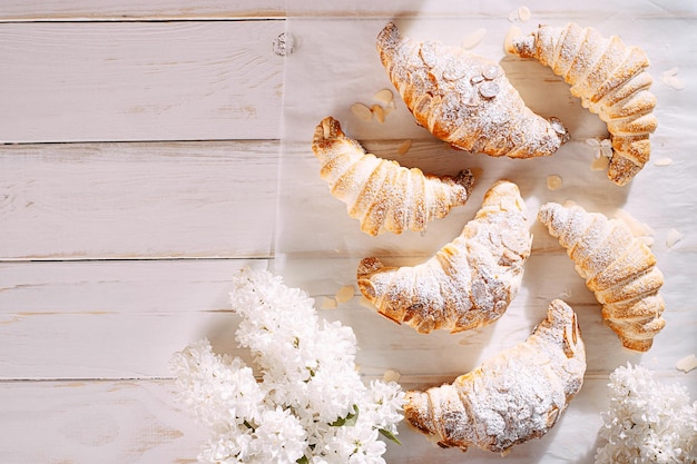 Foto frisches croissant mit mandelscheiben auf weißem holzhintergrund